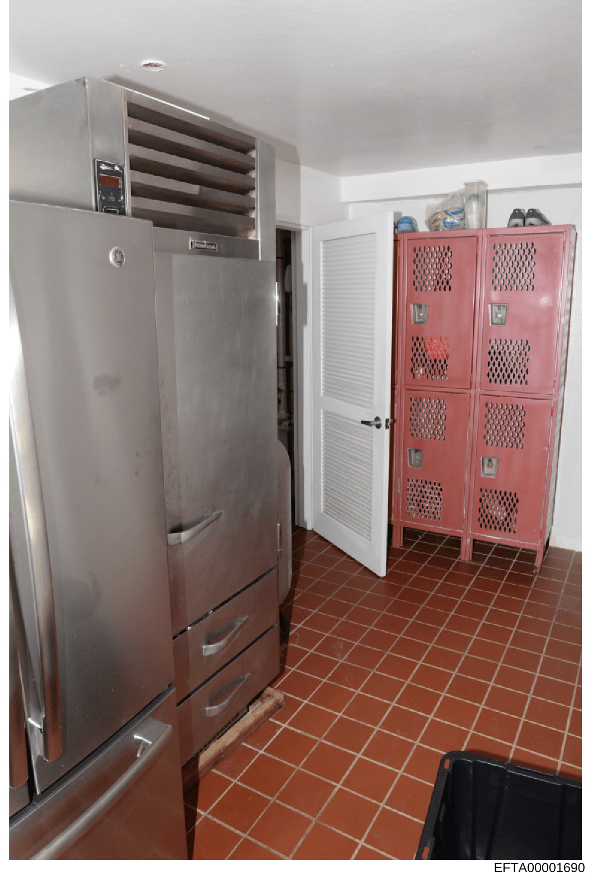 This is a photograph of a kitchen interior, likely from one of Jeffrey Epstein's properties, showing commercial-grade appliances including a large stainless steel refrigerator with upper ventilation unit and a distinctive pink multi-door storage lock