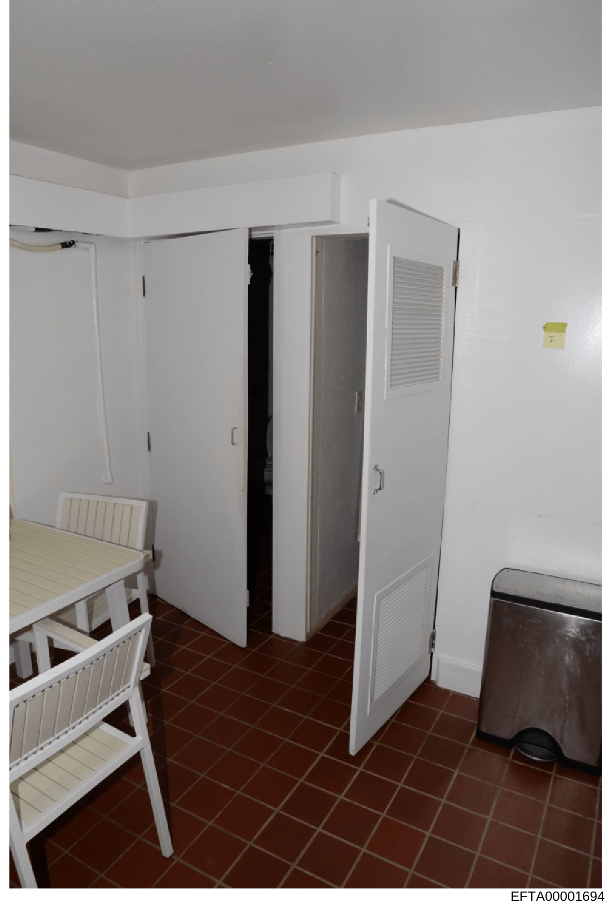 This is a photograph of an interior residential room, likely part of staff or guest quarters, showing two white bunk beds on the left side, a large white storage/utility cabinet in the center, and brown tile flooring throughout. The room appears to b