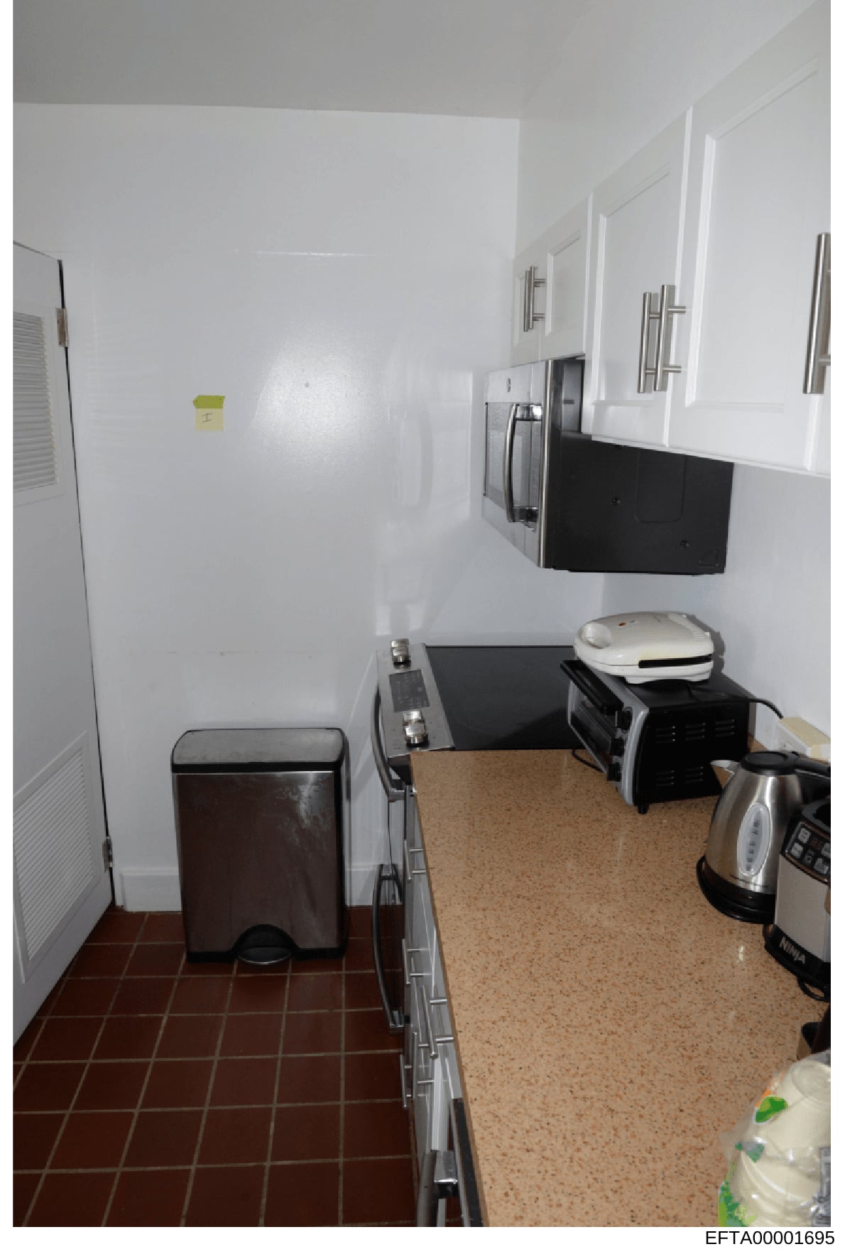 This is a photograph of a kitchen interior, showing appliances and cabinetry. The image appears to be from an evidence documentation of an Epstein property, with a Bates number indicating it is part of the DOJ investigation files. The kitchen feature