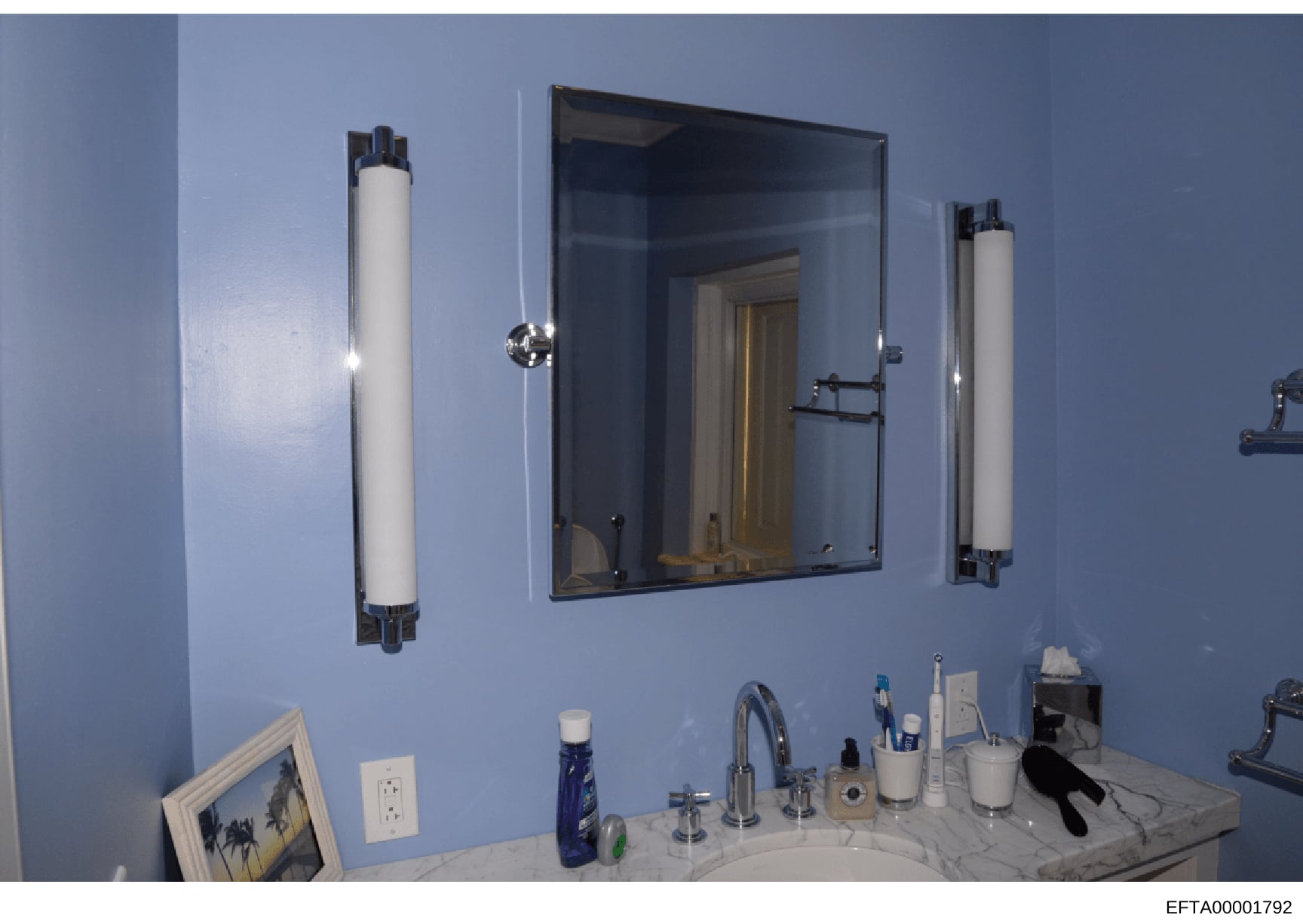 This is a photograph of a bathroom interior, showing a vanity counter with mirror and lighting fixtures. The image appears to be from a property inspection or inventory documentation, likely taken as evidence during the investigation of one of Jeffre