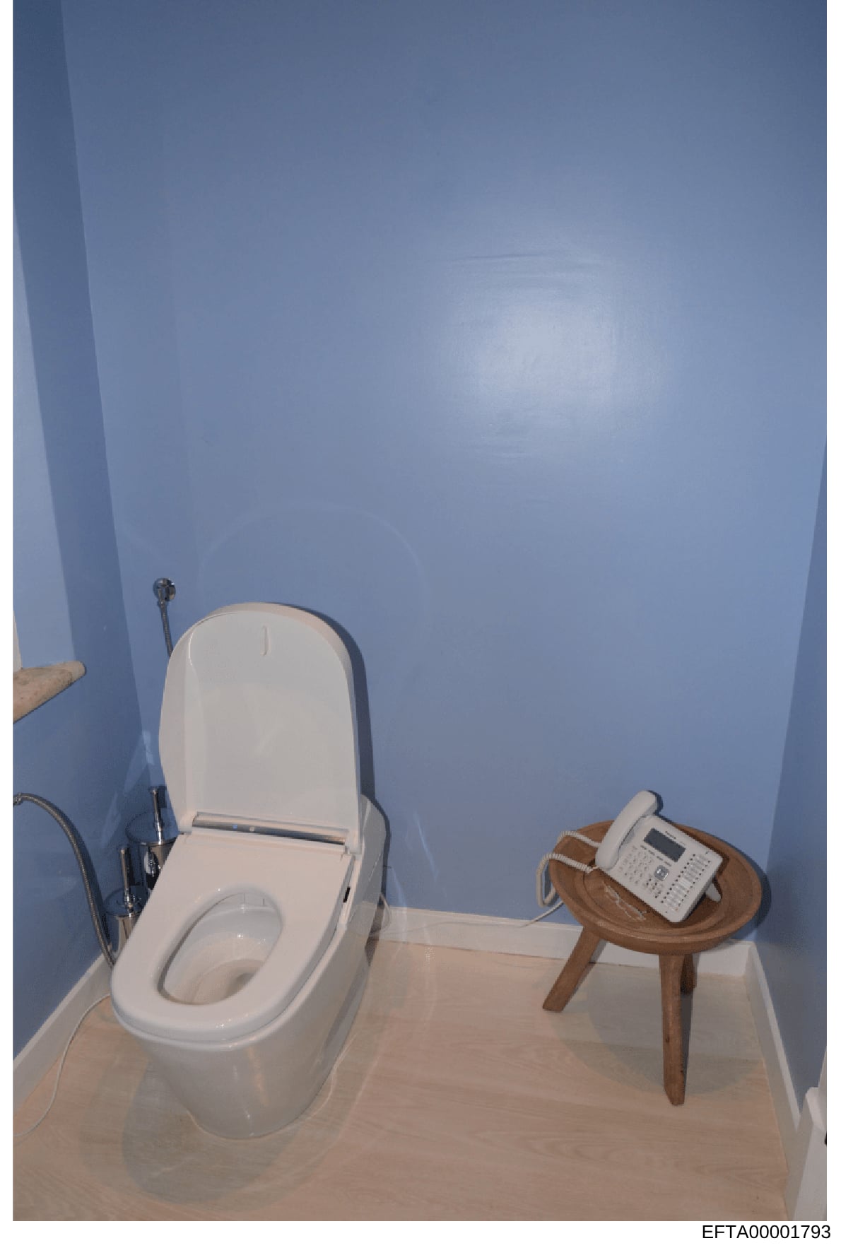 This photograph documents a bathroom interior featuring a high-end electronic toilet with bidet functionality and a wooden side table. The image appears to be taken as part of property documentation or evidence photography, showing fixture details in