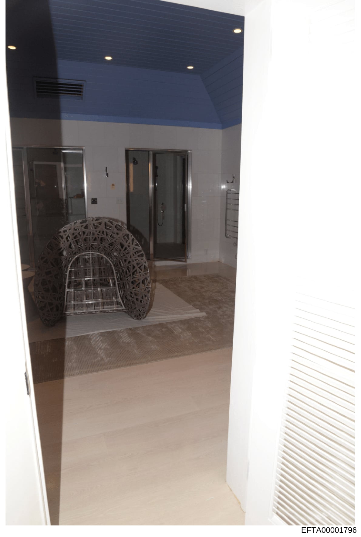 This is a photograph of an interior bathroom space showing contemporary design elements including a blue painted ceiling, recessed lighting, glass-enclosed shower, and modern fixtures. The image appears to be documentation of property interior condit