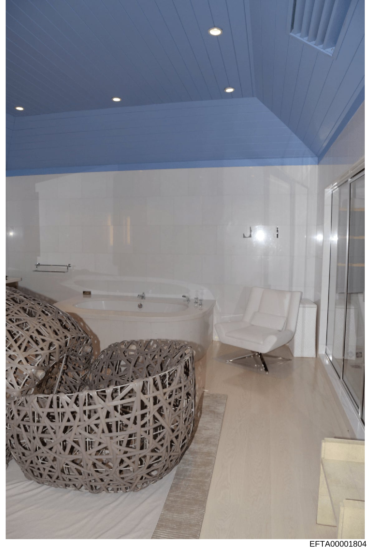 This is a photograph of a high-end bathroom interior featuring a large oval soaking tub, decorative woven seating elements, and modern furnishings. The image appears to be documentation of property interior design or features, likely from one of Epst