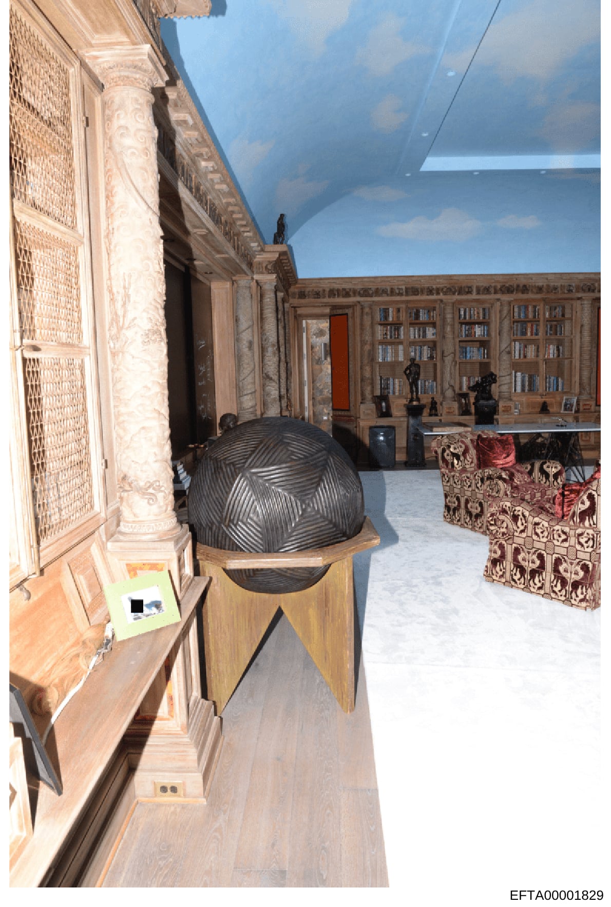 This photograph documents the interior of a high-end residential space, showing an ornately decorated room with classical architectural elements including decorative columns, built-in bookshelves, and art objects. The space appears to be part of a la