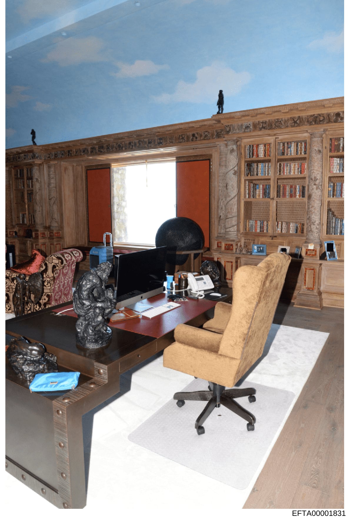 This photograph shows a luxuriously furnished office space with floor-to-ceiling wooden bookshelves, elaborate wood paneling with carved decorative details, an executive desk with office equipment, and various art objects and sculptures. The room fea
