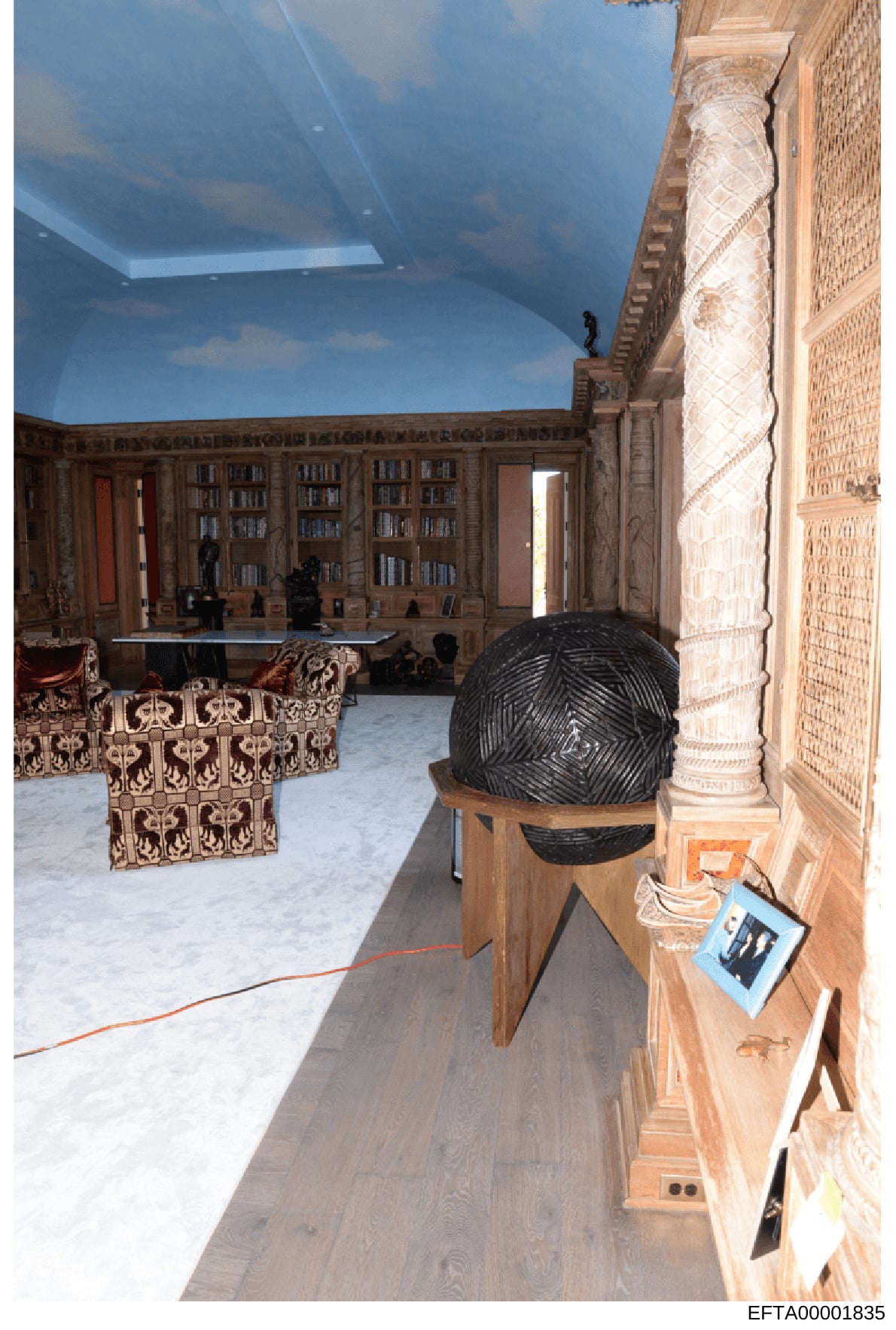 This is an evidence photograph depicting an ornate, high-end residential interior space featuring a library with extensive built-in wooden bookshelves, decorative elements, and a sky-lit ceiling. The room shows luxury furnishings including patterned 