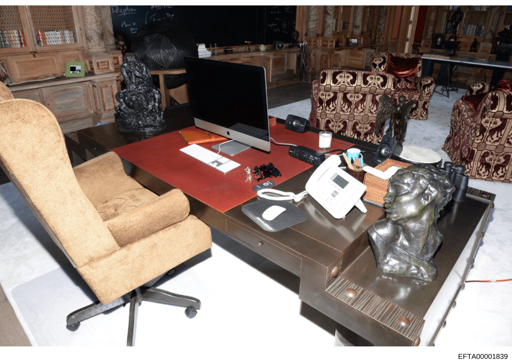 This is an evidence photograph showing a luxuriously appointed office interior with high-end furniture, artwork, and technology equipment. The space features ornate architectural details, expensive decorative objects including bronze sculptures, and 