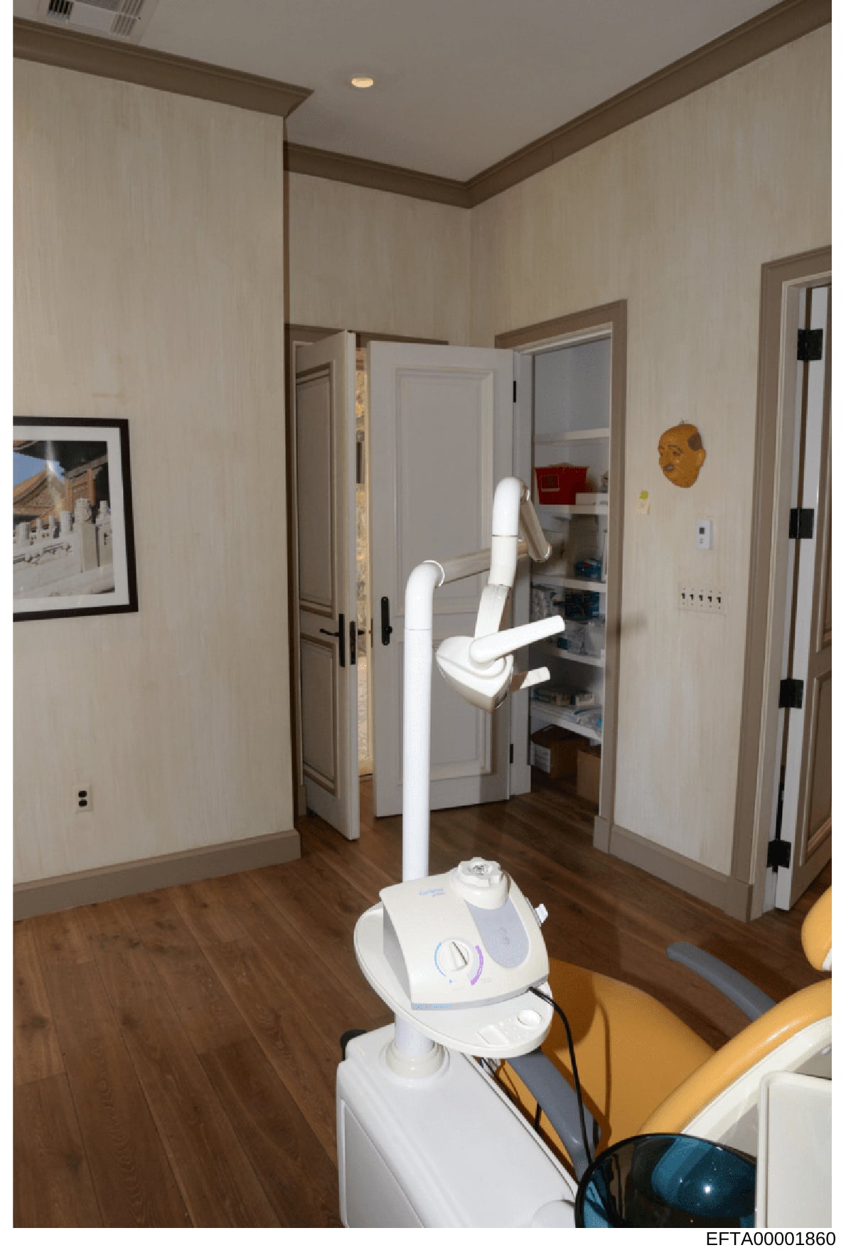 This photograph shows the interior of what appears to be a medical or dental treatment room, featuring professional equipment including a dental chair apparatus with articulated white arms, recessed lighting, modern finishes, and multiple doorways. T