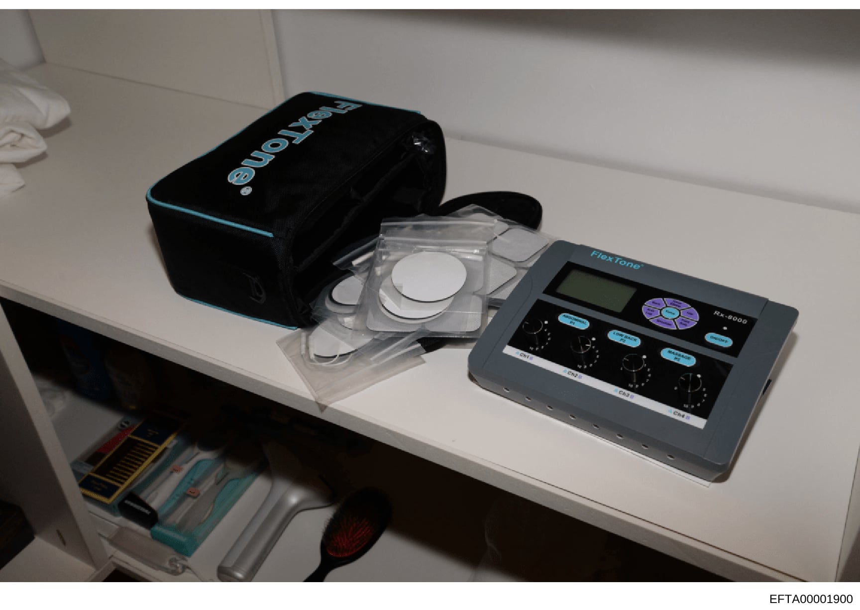 This photograph shows a white shelf or counter displaying professional facial analysis or skin analysis equipment, including a FitaFlone RX-8000 device with digital controls, optical measurement probes in a clear storage case, and a black carrying ca