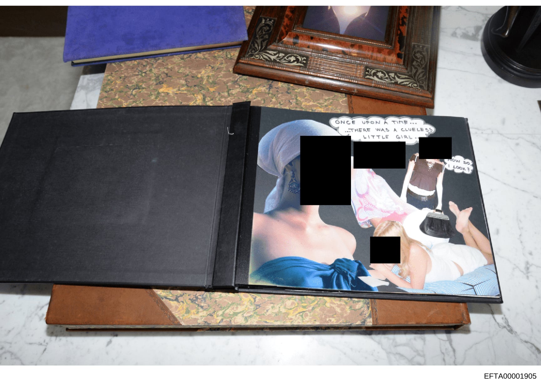 This is a photograph of a black portfolio or album containing an image with heavily redacted portions. The photo shows what appears to be evidence collected during the investigation, with significant portions blocked out. The visible text includes a 