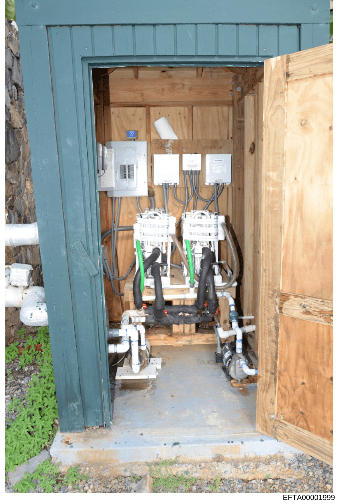 This is a photograph of the interior of a blue metal electrical equipment enclosure or utility box, showing various electrical components including circuit breakers, wiring, and distribution panels mounted on wooden backing. The image documents the e