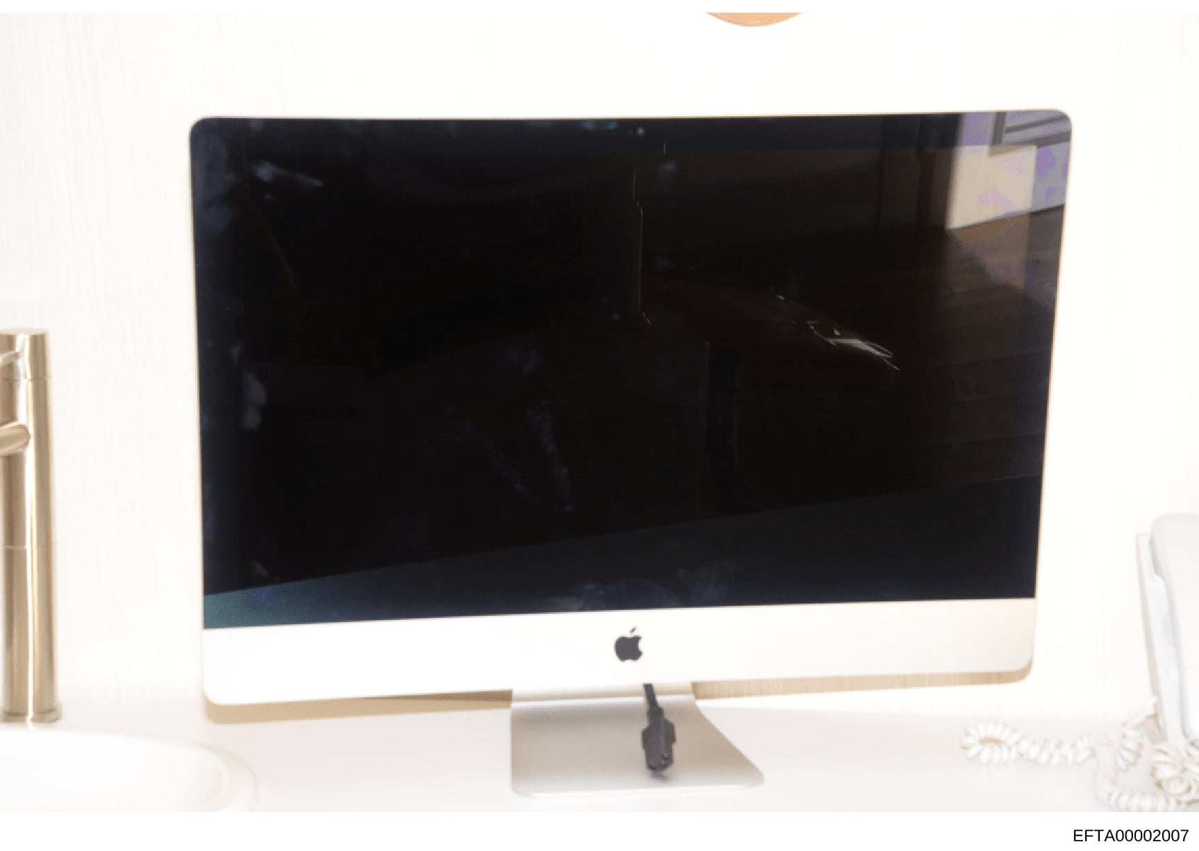 This is a photograph of an Apple iMac computer with a white bezel and aluminum stand, displaying a black screen. The photo appears to be evidence documentation from the Epstein investigation, likely seized during property searches. The computer's con