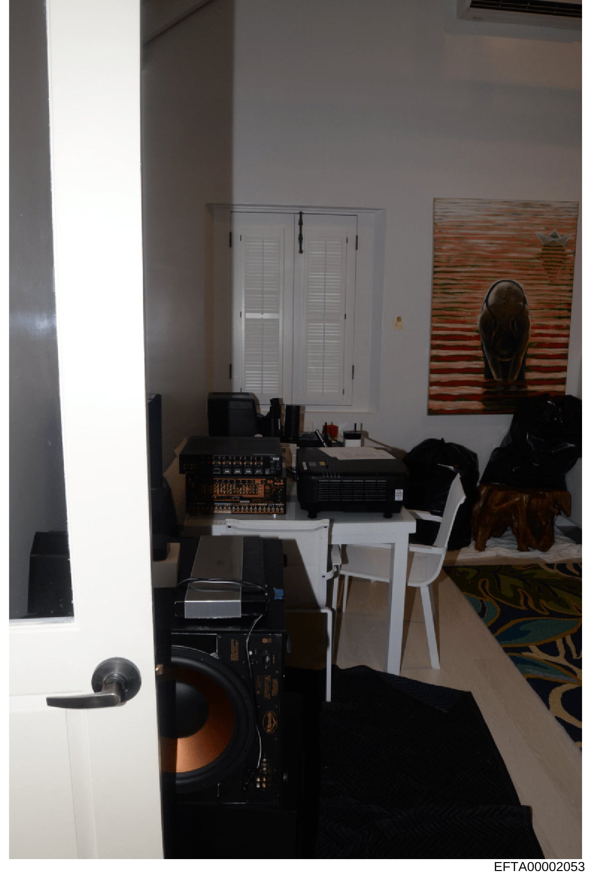 This is an evidence photograph depicting an interior room containing audio and electronic equipment. The room shows a white closet with louvered doors, professional audio equipment including what appears to be mixing boards and amplifiers on a white 