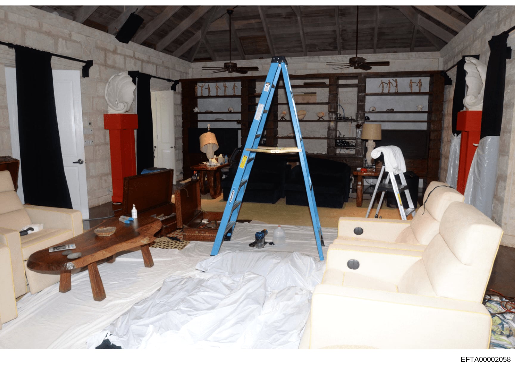 This photograph documents an interior space undergoing active renovation or construction, showing furniture protected with white sheeting, a blue ladder, and wooden shelving units. The image appears to be evidence documentation of one of Epstein's pr