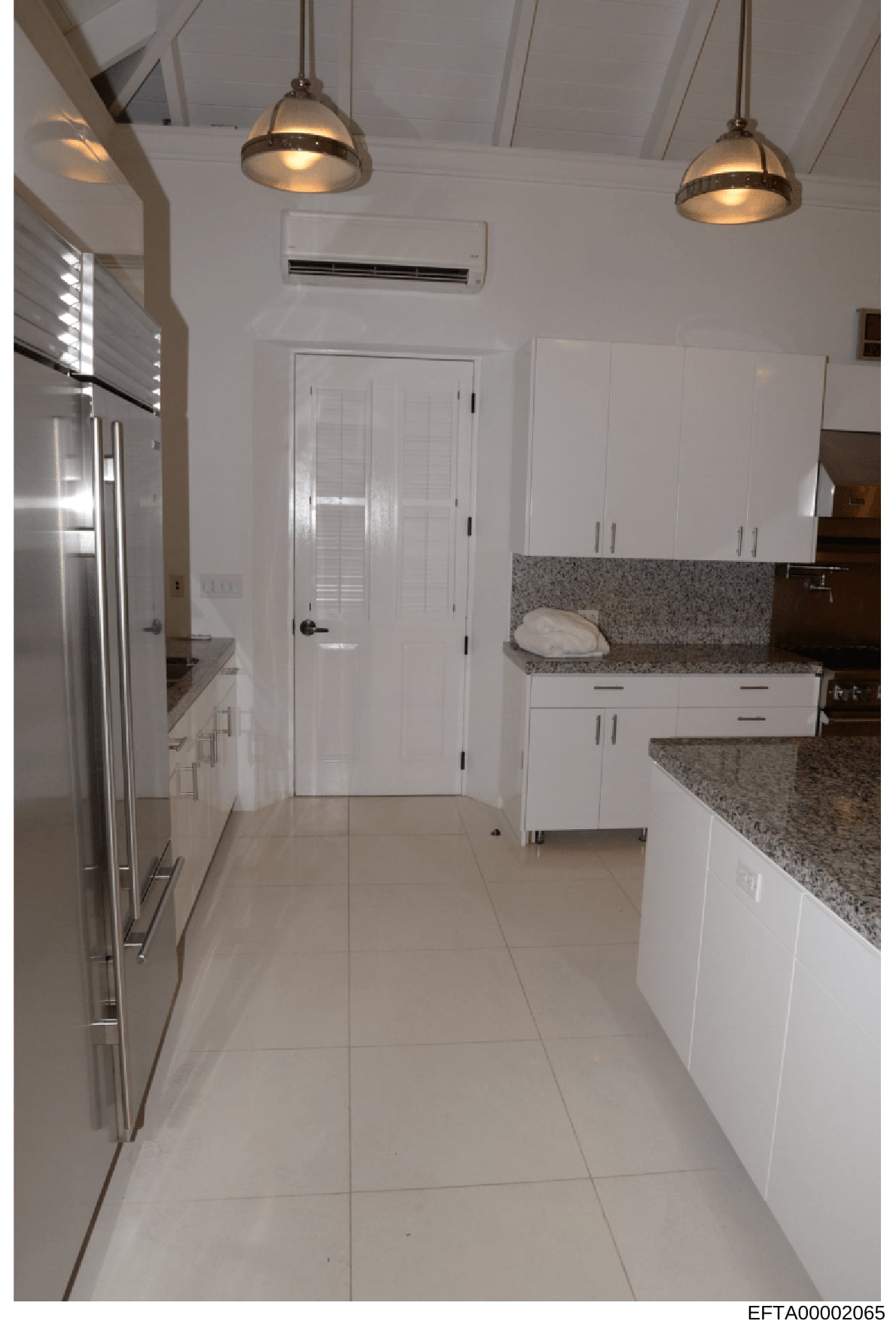 This is a photograph of a modern kitchen interior, showing contemporary design and finishes. The image captures white cabinetry, granite countertops, stainless steel appliances, pendant lighting, and tile flooring. This type of evidence photo would h