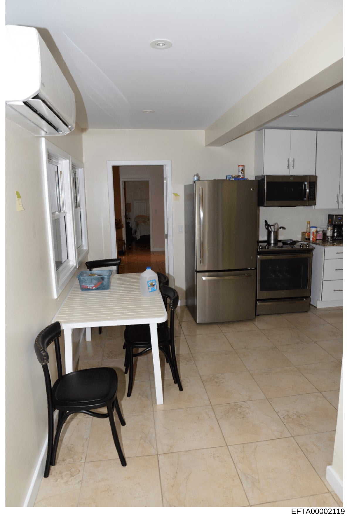 This is a photograph of a modern kitchen interior, likely taken as part of property documentation or evidence collection in the investigation. The kitchen features standard appliances, a dining table, and appears to be a residential space. The image 