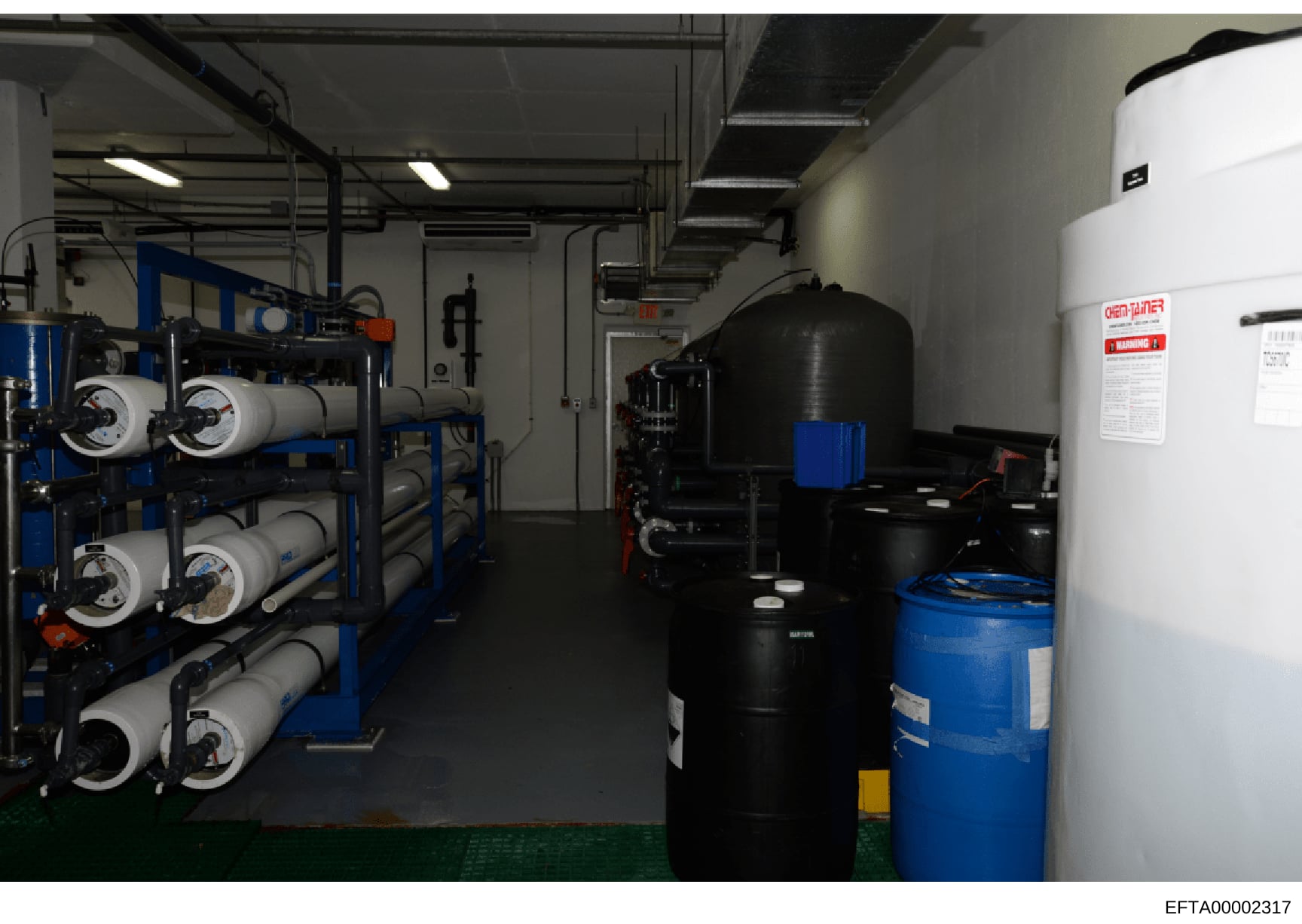 This photograph shows an industrial or commercial mechanical room, likely part of an Epstein property, containing water filtration and treatment equipment including multiple filter vessels, storage tanks, and plumbing infrastructure. The image docume