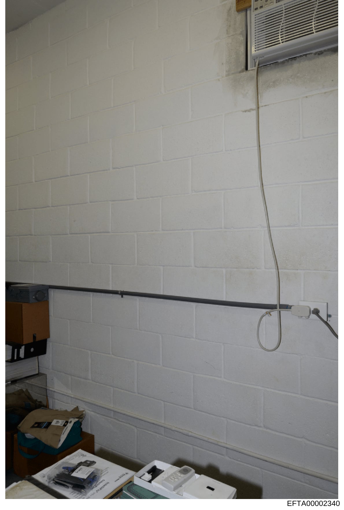 This is an evidence photo from the Epstein investigation showing an interior room with white subway tile walls, electrical wiring, outlets, and what appears to be an air conditioning unit. The image captures basic room infrastructure and appears to b