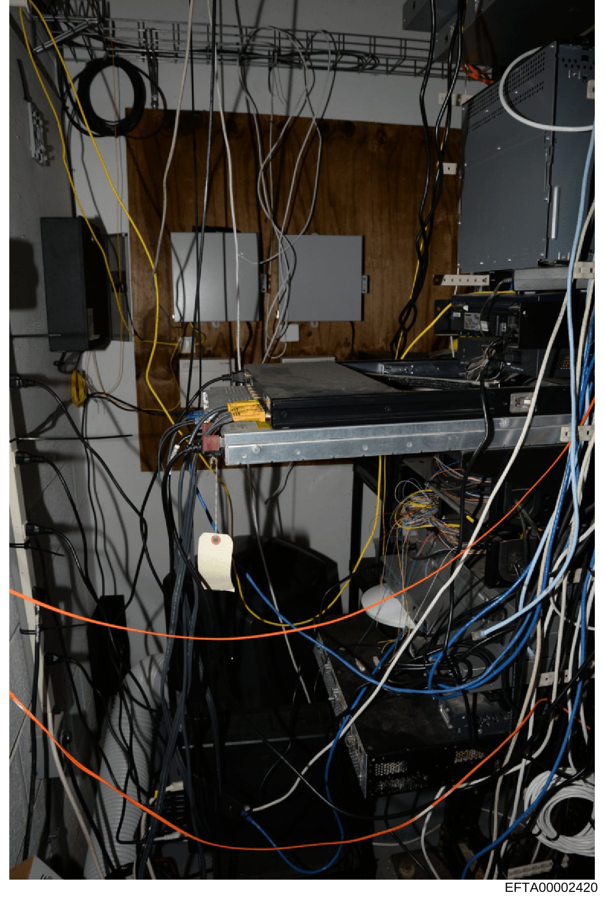This photograph shows an interior view of a computer server room or technical installation space containing multiple networking and server equipment with extensive cable management. The image documents various hardware components including servers, n