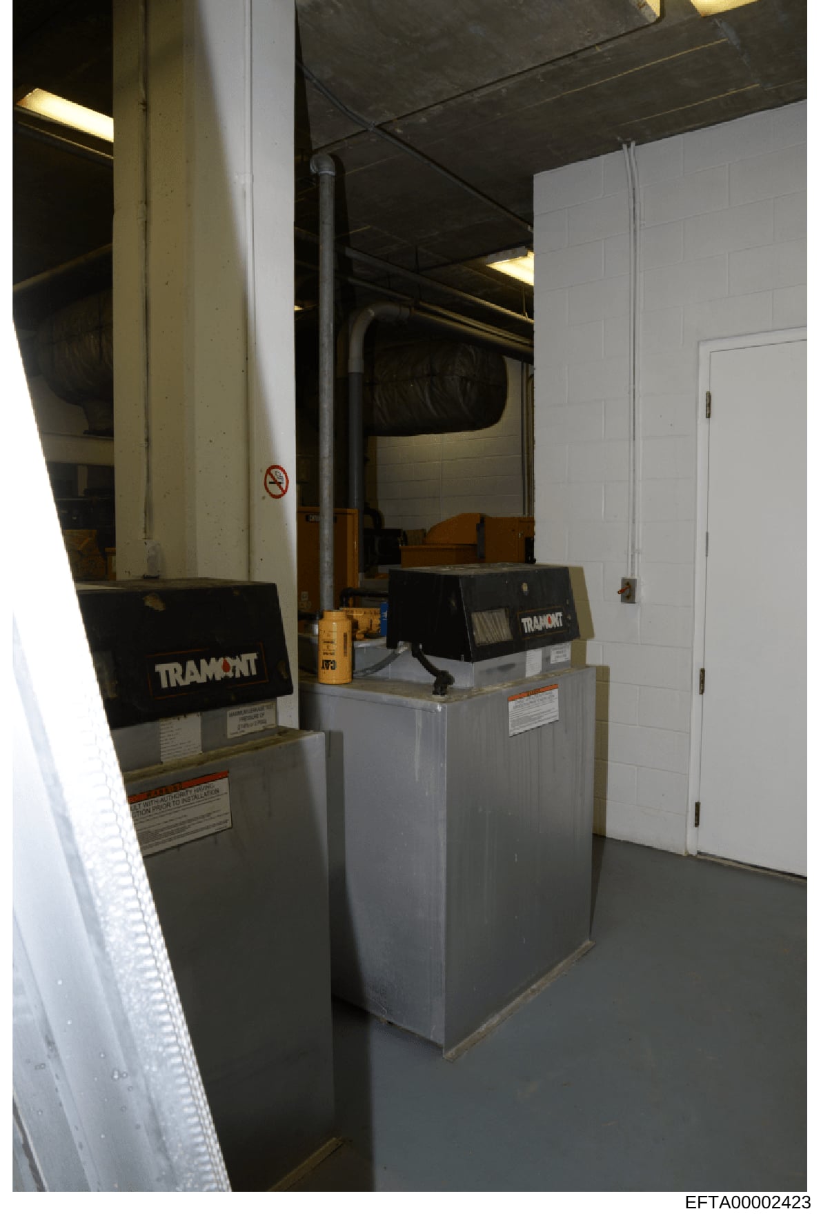 This is an evidence photograph showing the interior of a mechanical room or basement space containing heating, ventilation, and air conditioning (HVAC) equipment branded 'Tramont.' The photo documents industrial-scale climate control systems, likely