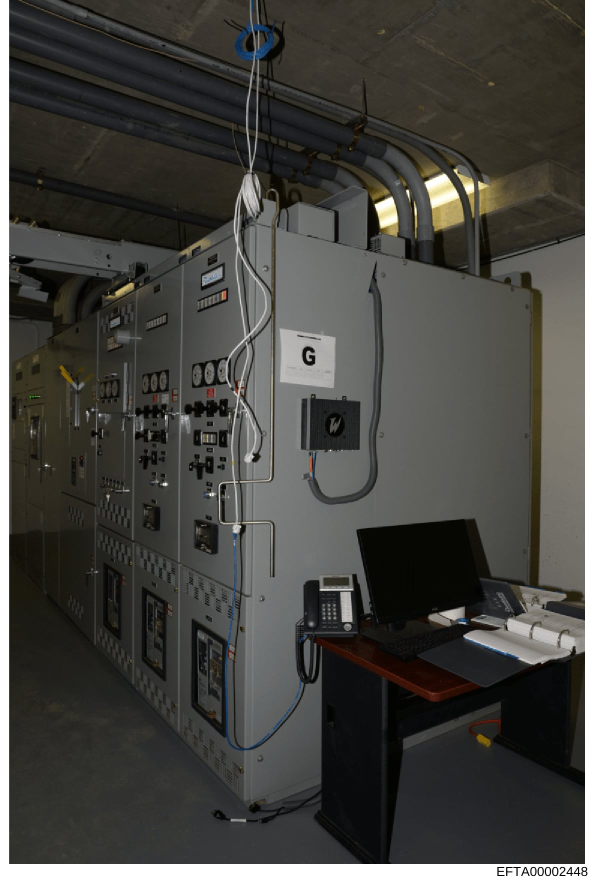 This photograph shows an industrial control panel system labeled with 'G' in what appears to be a facility equipment room or control center. The image captures electrical control panels with various switches, indicators, and control mechanisms, along