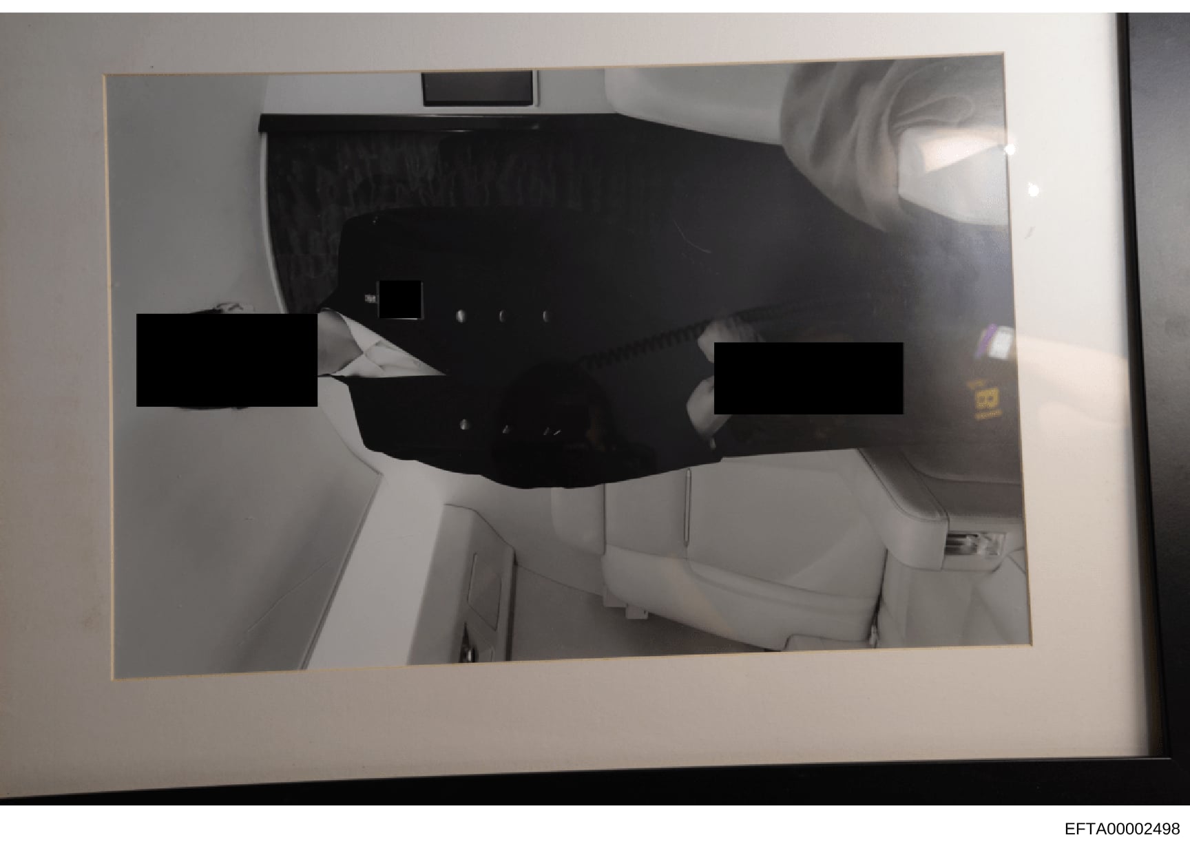 This is an evidence photograph showing the interior of an aircraft cabin, likely from Epstein's private jet. The image shows two individuals whose faces and identities are heavily redacted with black rectangles. The cabin features white leather seati