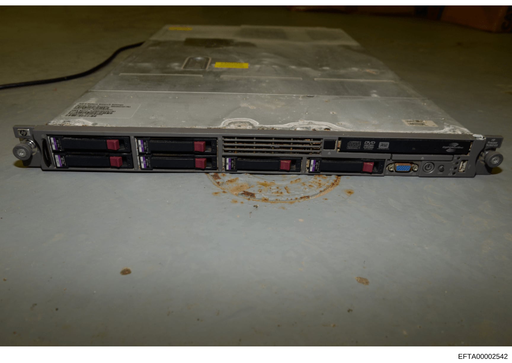 This photograph depicts a rack-mounted server unit (appears to be an HP ProLiant or similar enterprise server) with four hot-swappable hard drive bays containing red hard drives, captured as physical evidence during the investigation. The device show