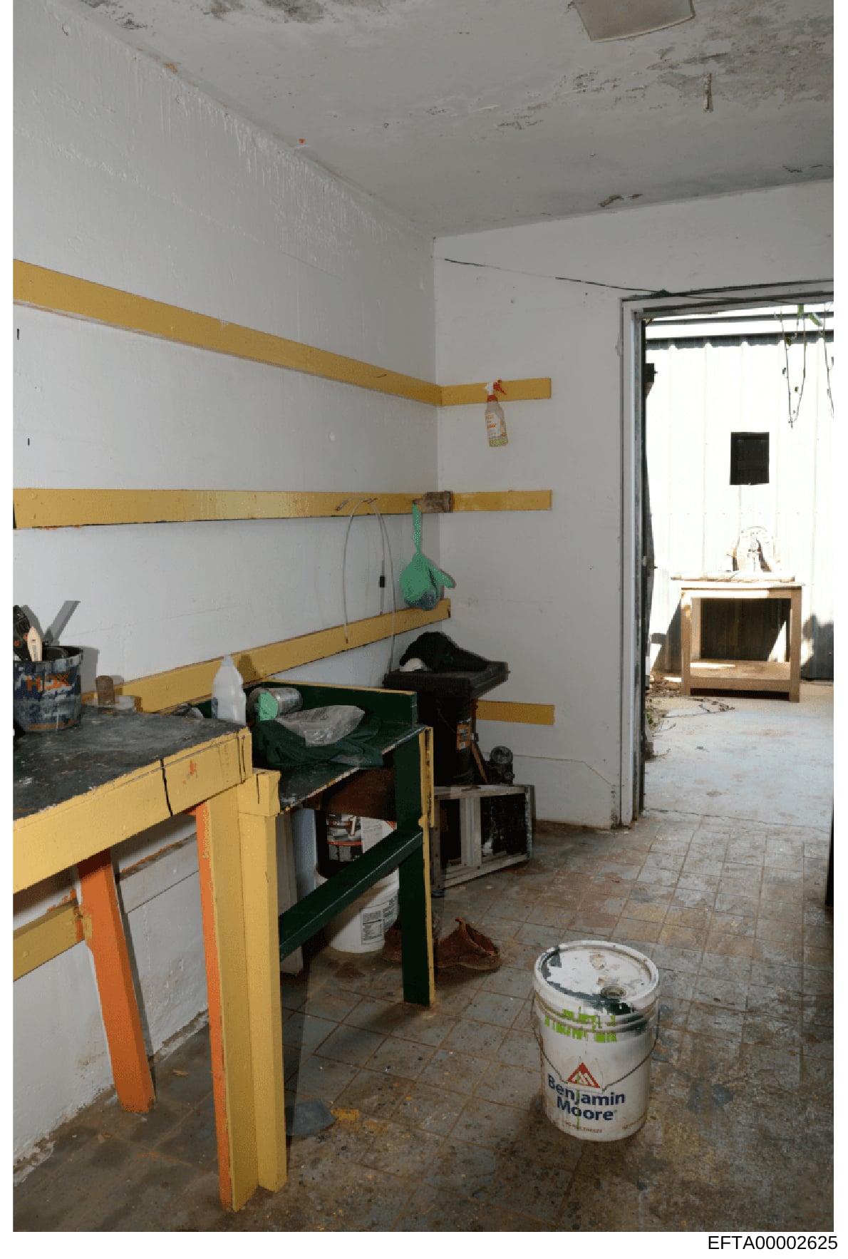 This photograph documents an interior space undergoing construction or renovation, featuring yellow wooden framing on walls, exposed materials, and basic furnishings. The room appears to be in a state of renovation with visible work-in-progress eleme