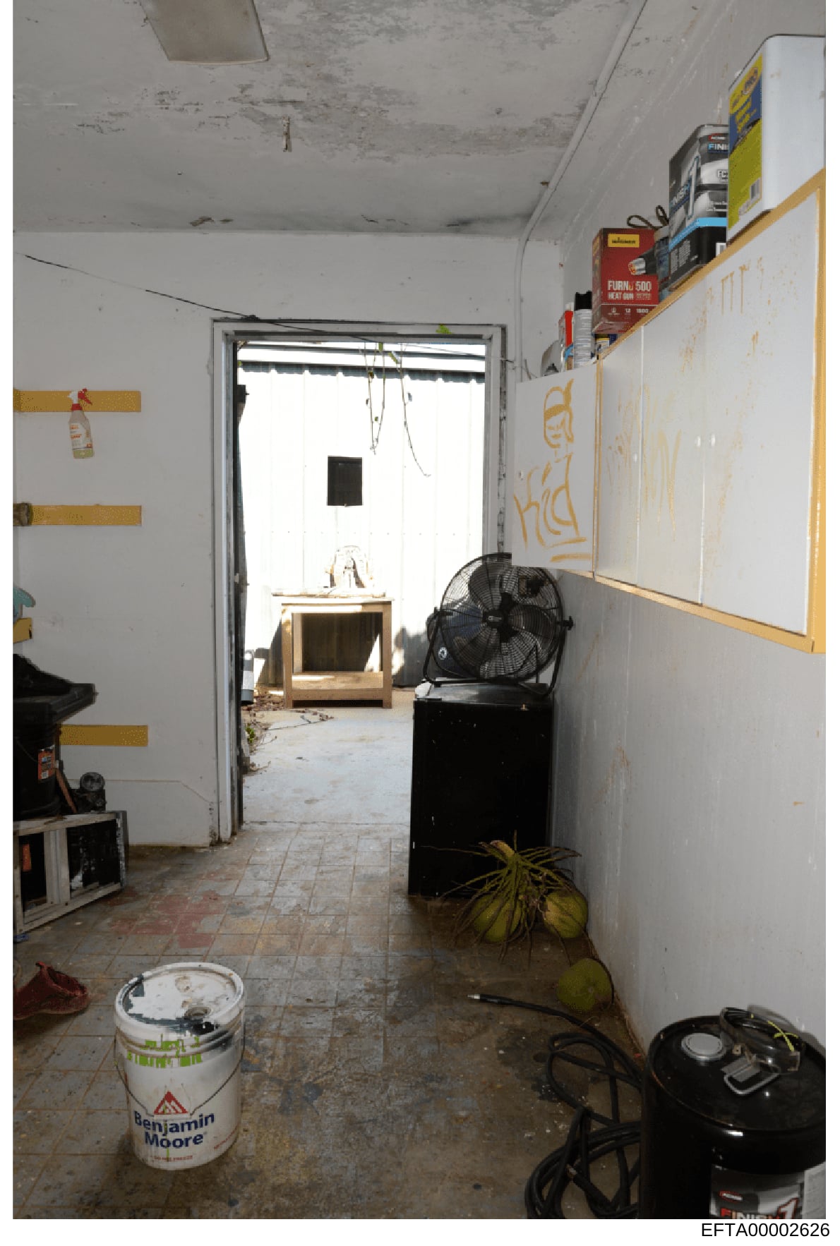 This photograph documents an interior room in what appears to be a property under renovation or construction. The space shows exposed ceiling, damp walls, construction materials, and various equipment scattered throughout, suggesting the room was in