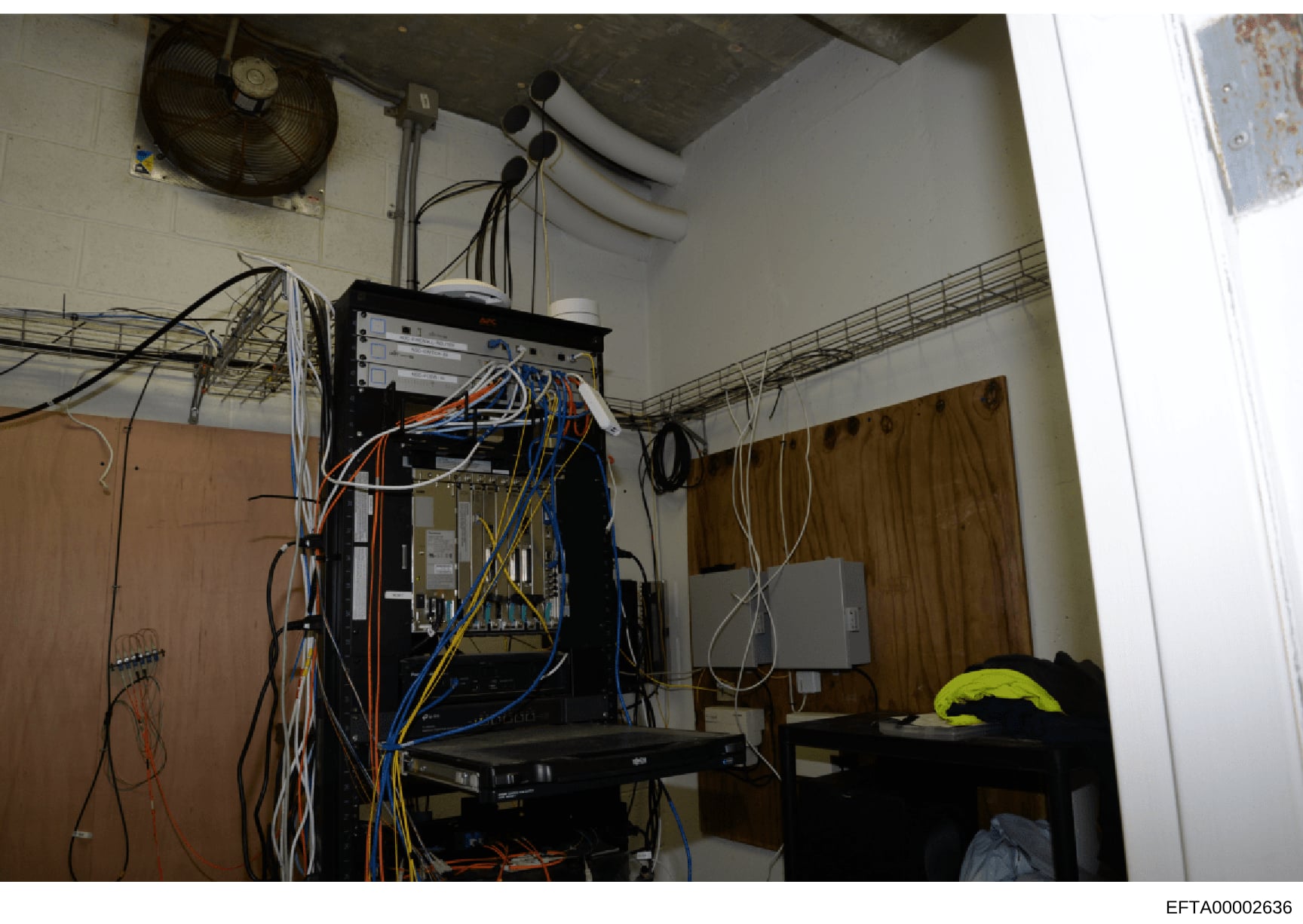 This photograph documents a room containing networked computer equipment, servers, and telecommunications infrastructure with multiple cable connections. The image shows a technical installation space with cooling systems, electrical wiring, and netw