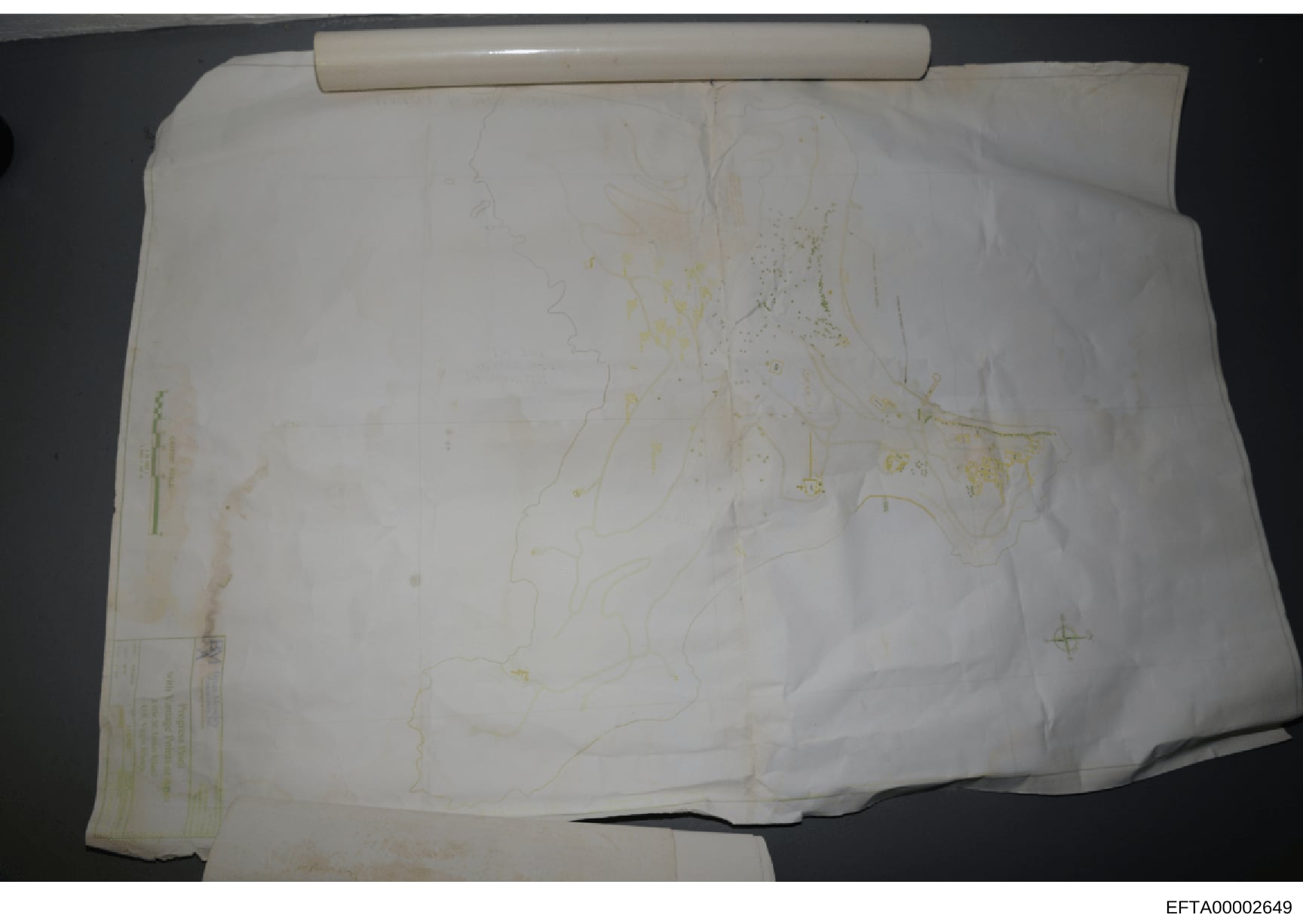 This is a photograph of a rolled architectural blueprint or property map document, yellowed with age and showing faint sketch lines and annotations. The document appears to be a historical architectural or property plan, possibly relating to one of E