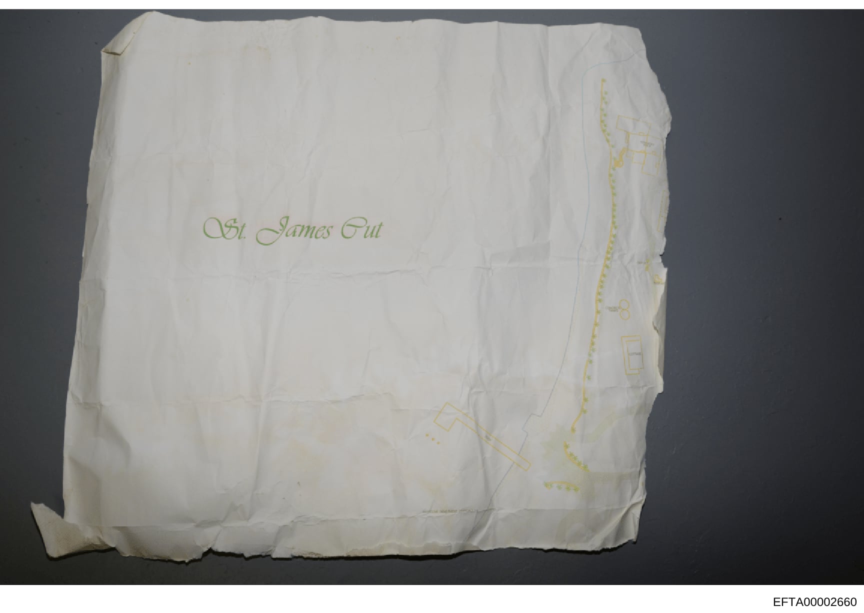 This is a photograph of what appears to be a white linen or paper architectural drawing cover or blueprint folder bearing handwritten text in cursive reading '94 James Gut' in gold or yellow ink. The item shows fold lines and wear consistent with age
