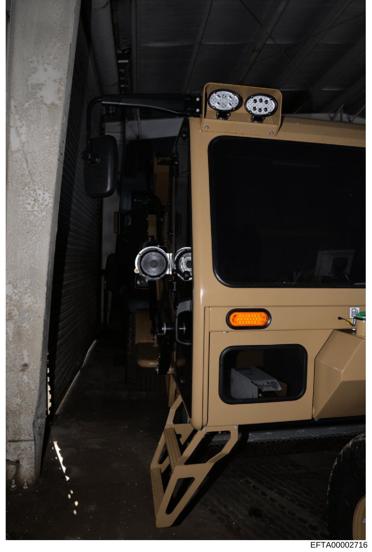 This photograph shows a tan or beige-colored vehicle, possibly a Hummer or similar large SUV, parked in what appears to be an underground parking structure or covered garage. The vehicle is equipped with roof-mounted LED lighting fixtures and is posi