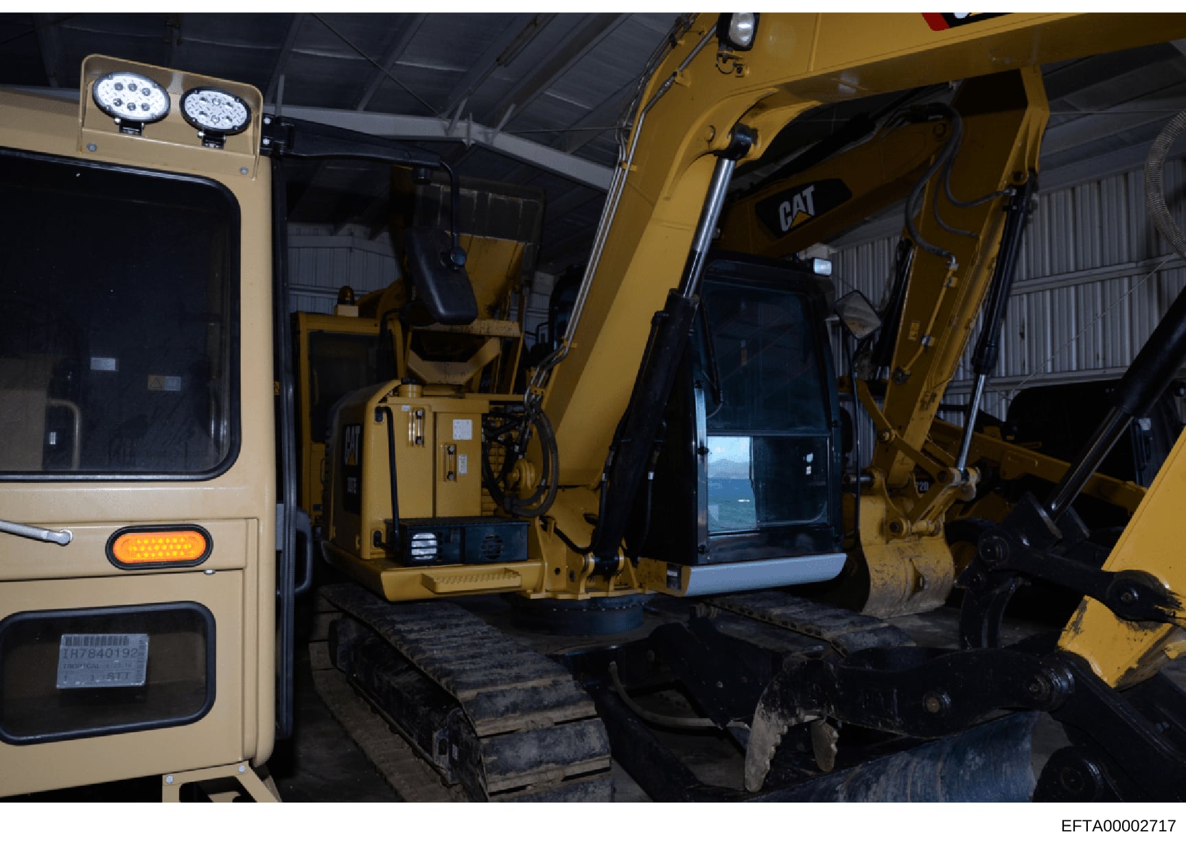 This photograph shows the interior cabin of a yellow Caterpillar (CAT) excavator or similar heavy construction equipment, displaying the operator's seating area, control systems, and instrumentation. The image appears to be documentation of equipment