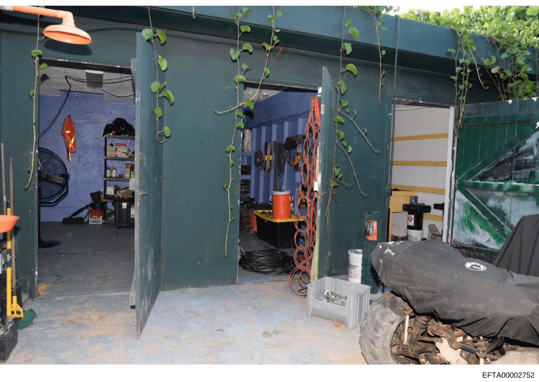 This is a photograph of the interior of a green-painted storage shed or container structure. The space contains various tools, equipment, and storage items including bicycles, shelving units, orange and red equipment (possibly recreational or mainten