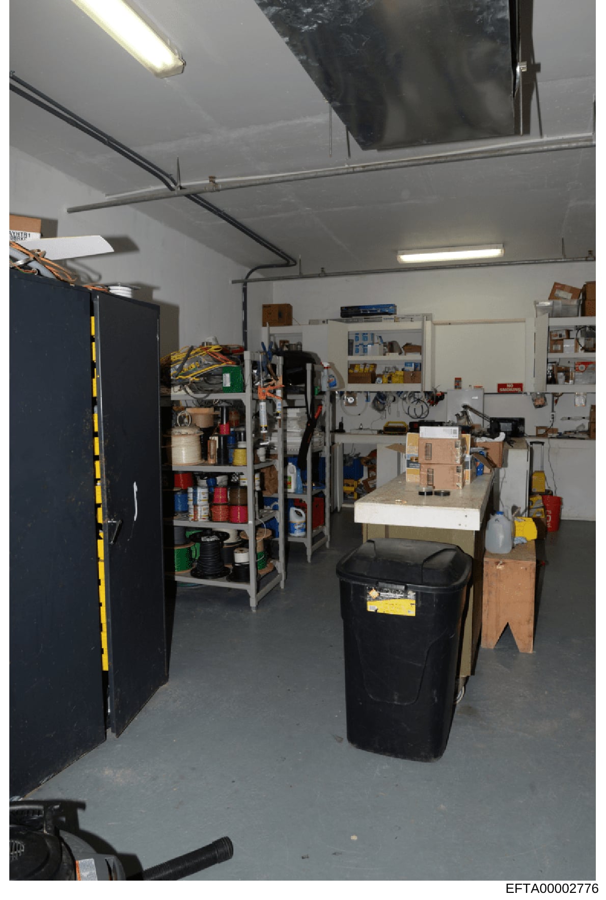 This is an evidence photograph showing the interior of a garage or workshop space, likely taken during the investigation. The image documents the contents and layout of a storage area containing various tools, supplies, shelving units, and miscellane