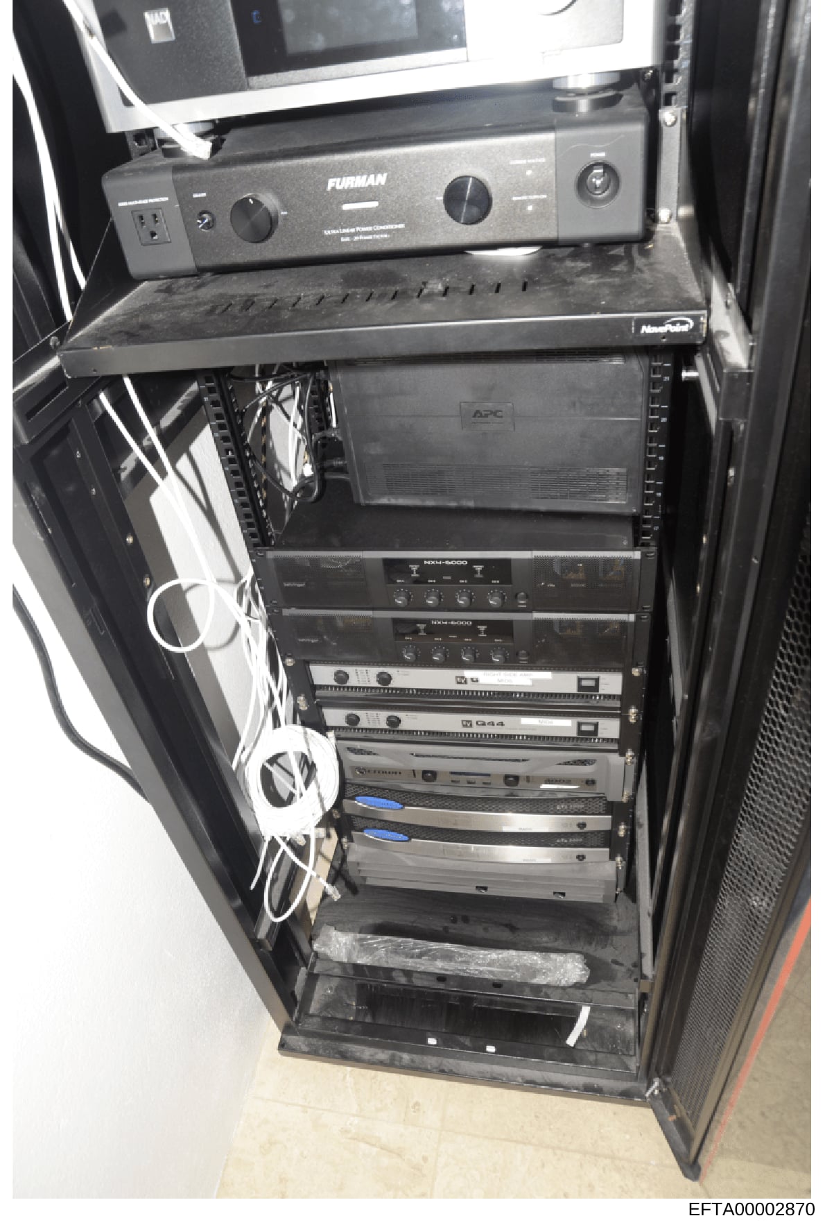 This photograph depicts a professional equipment rack containing audio amplifiers, APC power management systems, and related electronic components. The image shows the interior setup of technical infrastructure, with visible Furman power conditioner 