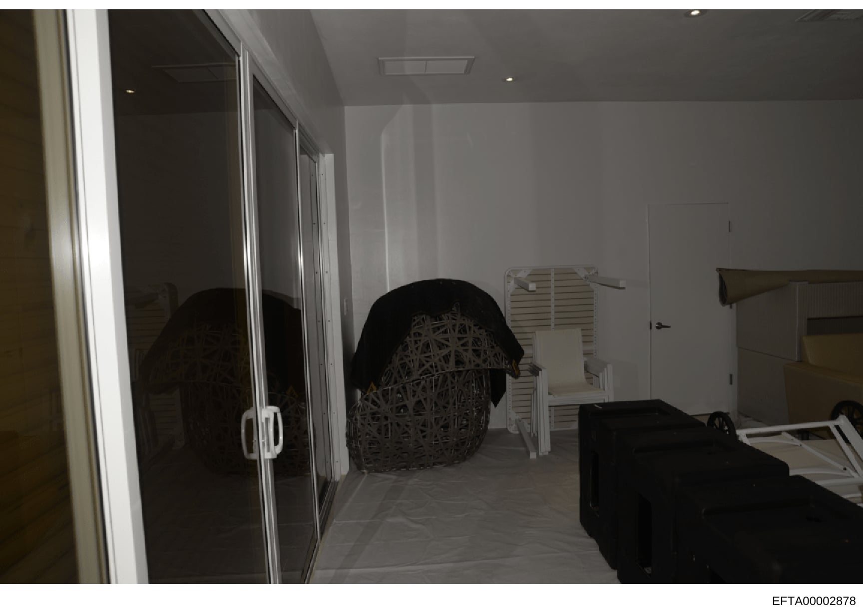 This is a photograph of an interior bedroom space, likely from one of Epstein's properties documented during the investigation. The image shows a modern room with sliding glass closet doors, white walls, recessed lighting, and various furniture and s