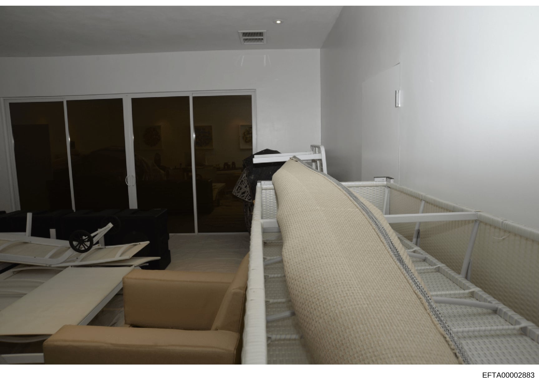 This is an evidence photograph of an interior residential space, showing a modern bedroom or suite with white walls, built-in closets with dark glass doors, tan/beige upholstered furniture, and what appears to be cribs or infant beds. The clean, cont