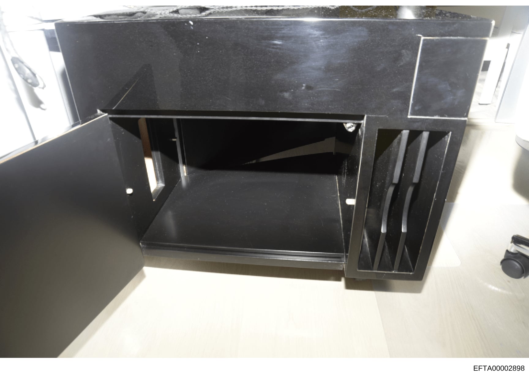 This is a photograph of a black desk with built-in storage features, including a hutch-style upper section and side filing or storage compartments. The image appears to be evidence documentation from a property search or seizure, likely taken during 