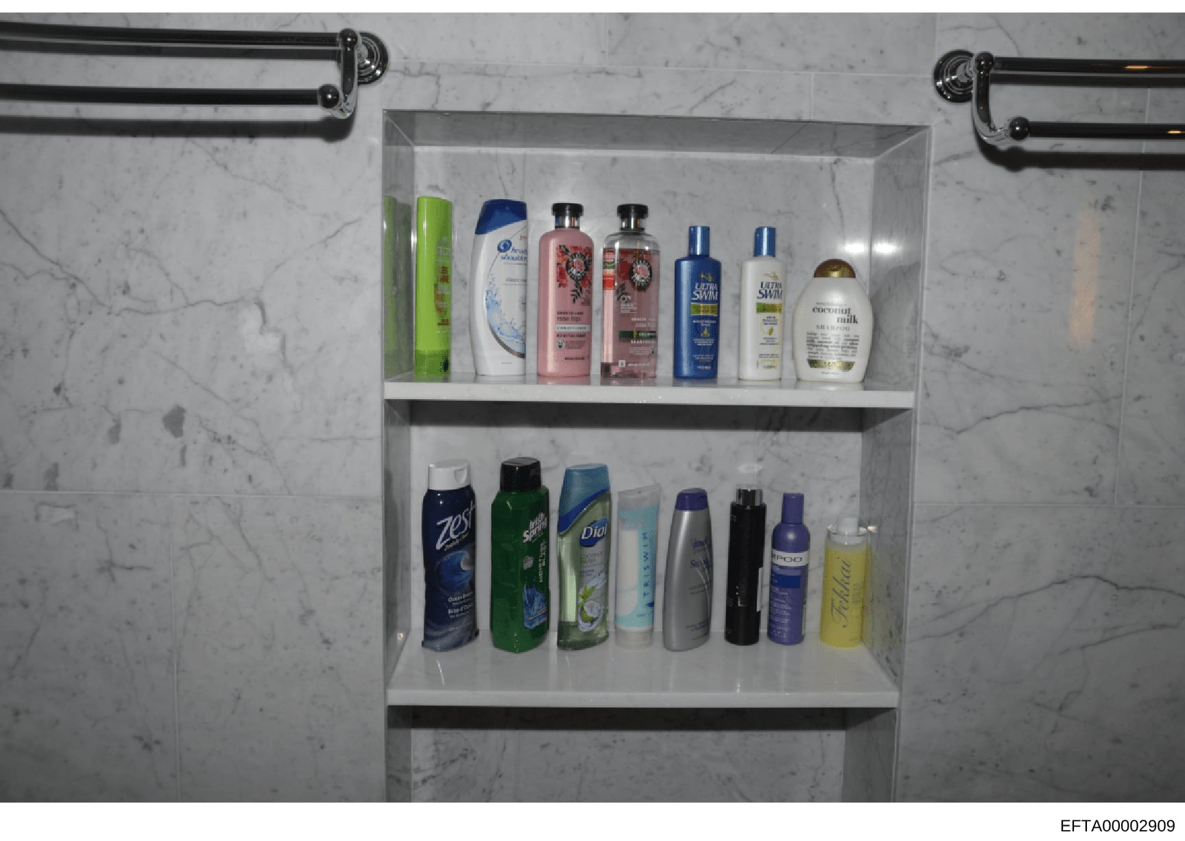 This is a photograph of a bathroom shelf unit displaying an array of personal care products including hair care items, body washes, deodorants, and other hygiene products. The image appears to be evidence documentation from a property search, showing