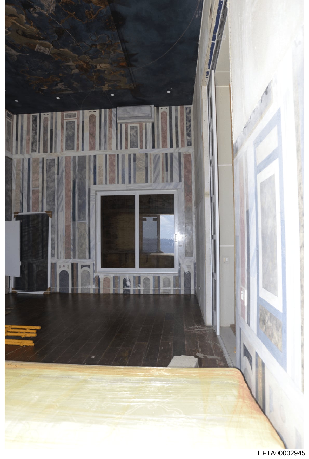 This is a photograph of an interior room showing striped wallpaper in muted tones, a dark ceiling, and what appears to be a window or glass door. The image is taken from a doorway looking into the room. The photograph appears to be evidence documenta