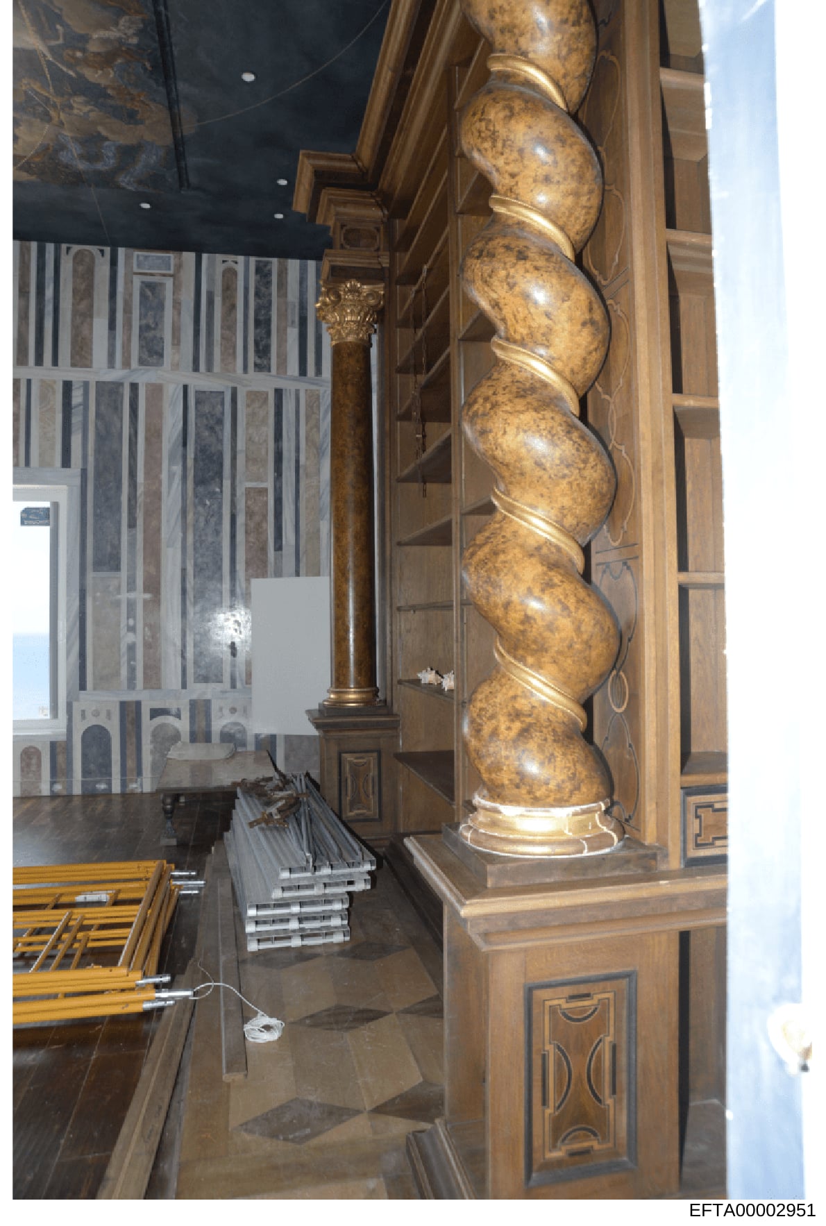 This photograph shows the interior of a luxury residential property, featuring ornate architectural details including decorative wooden cabinetry, a large gilt column with classical proportions, and high-end furnishings. The image appears to be docum