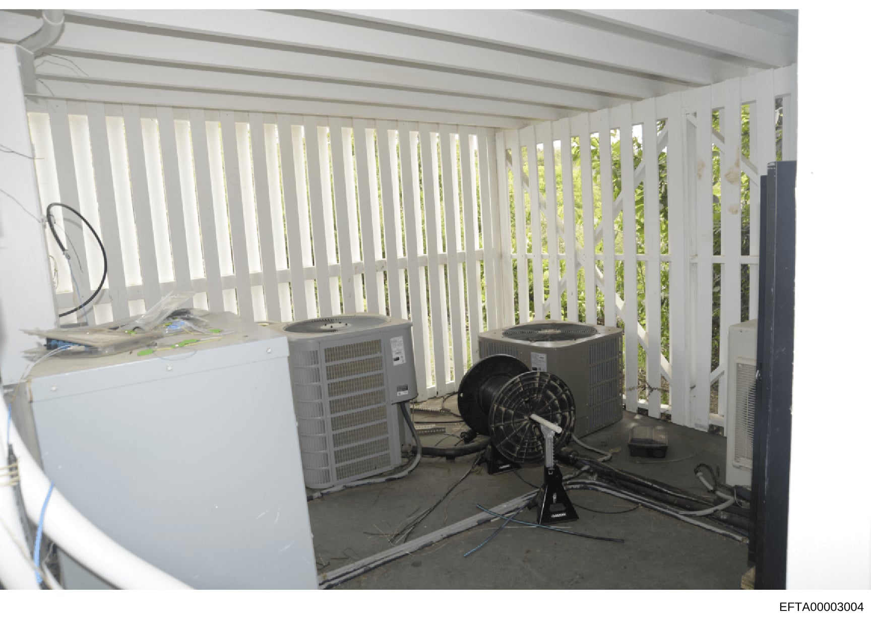 This photograph shows an interior equipment or utility room containing multiple HVAC units, air conditioning systems, and ventilation equipment. The room features white vertical blinds or louvers, concrete flooring, and various mechanical systems in