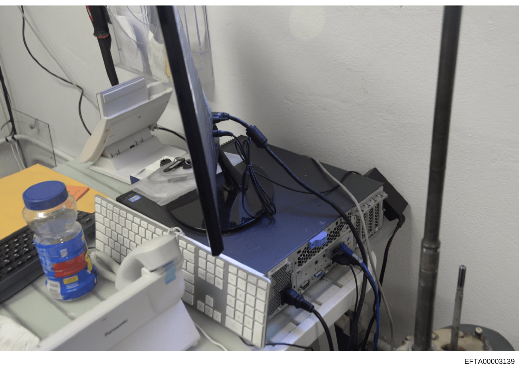 This is a photograph of a computer workstation setup featuring multiple monitors, keyboards, and server equipment with network cables. The image shows IT infrastructure that may have been used for data storage, communications, or business operations 