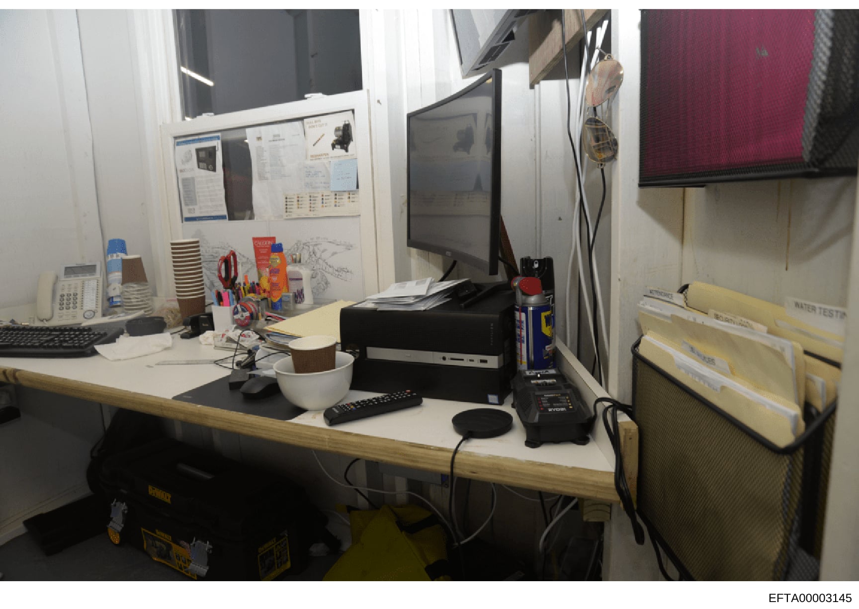 This is a photograph of an office workspace, likely from one of Epstein's properties or related locations documented during the investigation. The image shows a desk setup with computer equipment, monitors, file storage, and office supplies. The work