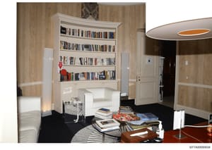 This is a professional 3D interior design rendering or architectural visualization showing a modernly furnished residential room with built-in bookshelves, seating area, and contemporary furnishings. The image appears to be part of property documenta
