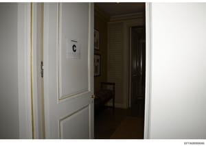This is an investigative photograph showing an interior doorway marked with evidence identifier 'C'. The image captures a white door with gold trim leading into a room with wallpapered walls and what appears to be furniture visible in the background.