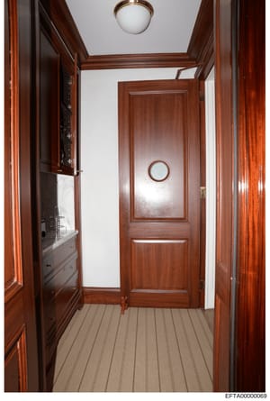 This is a photograph of an interior hallway featuring rich mahogany wood paneling, ornate wooden doors, and built-in cabinetry. The image appears to be from a property documentation or evidence photo collection related to the investigation, showing t