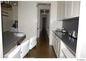 This photograph shows a modern kitchen interior with white cabinetry, dark granite countertops, and stainless steel appliances. The image appears to be from an inventory or property documentation, showing a galley-style kitchen layout with two seatin